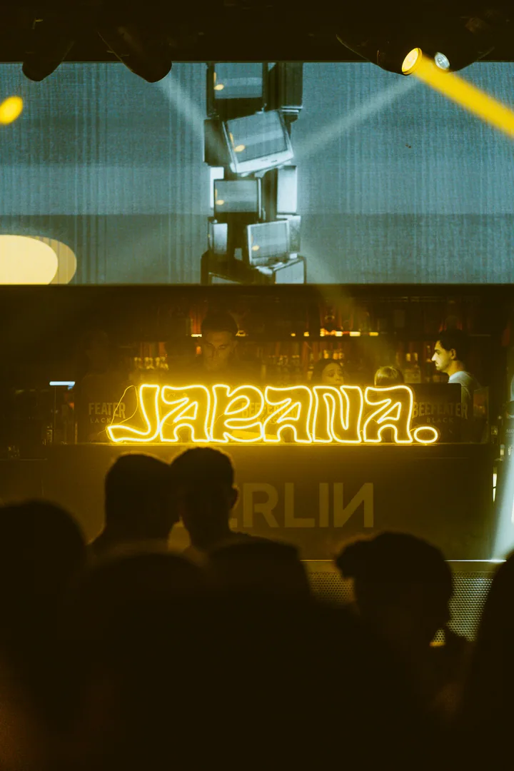 Escenario de Berlin Social Club con pantalla, focos y el neón de JARANA.